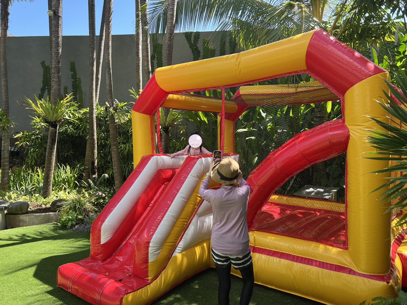 Playing on the garden's inflatable water slide, with mom watching 