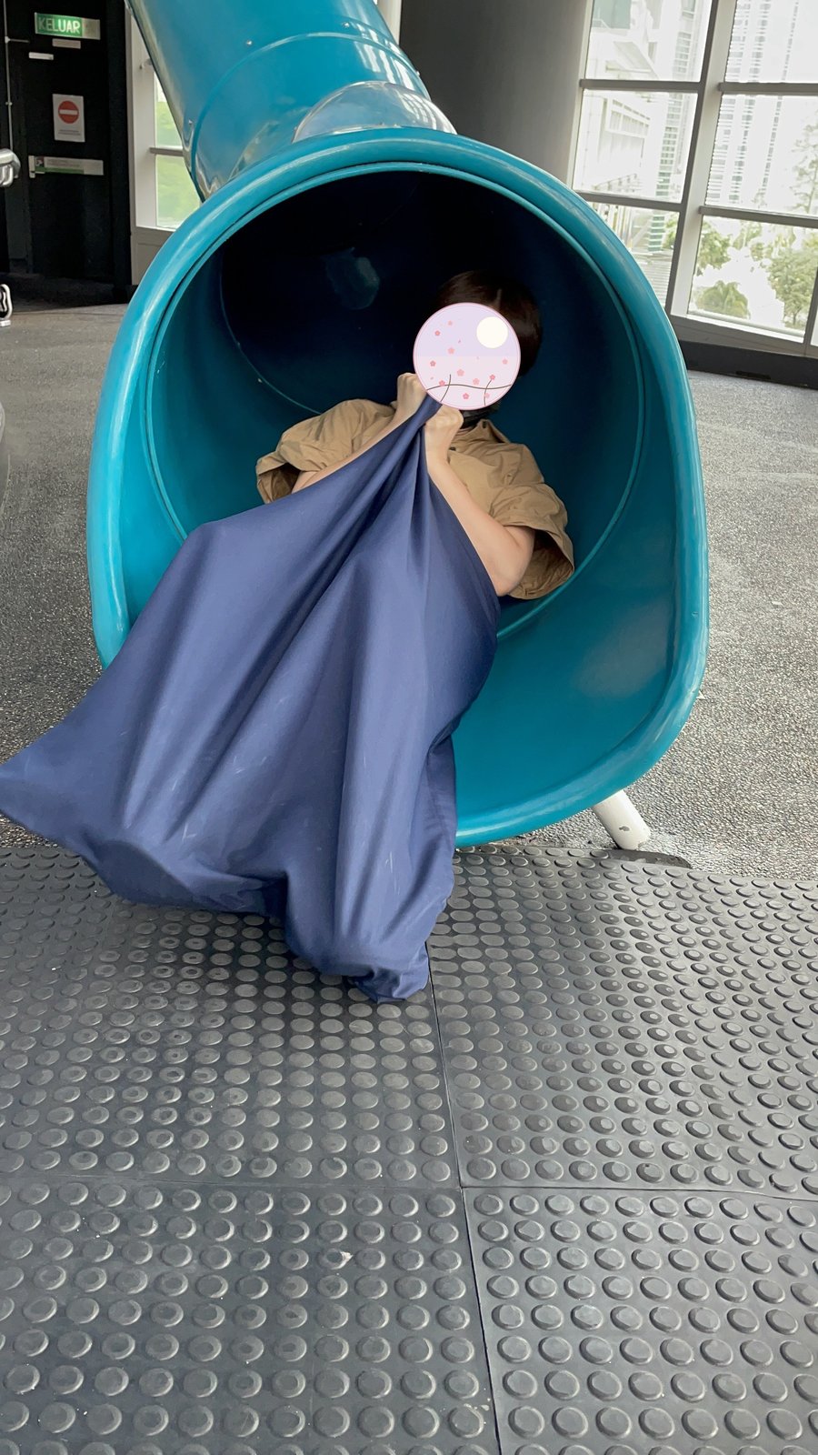 トンネル型の滑り台で布にくるまって遊ぶ様子