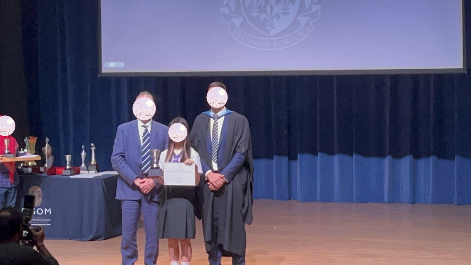 表彰式で先生からトロフィーと賞状を受け取る様子